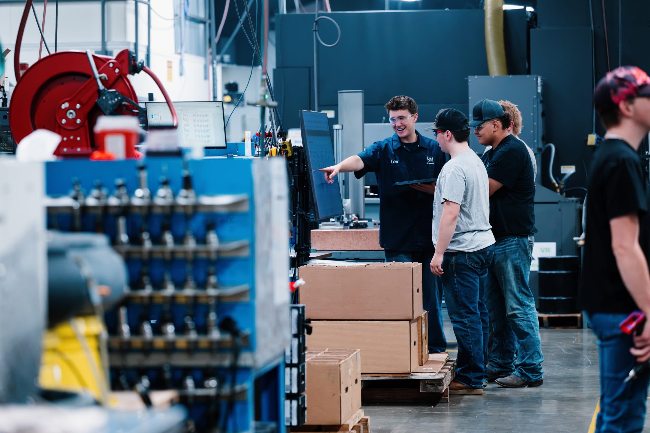 Team members talking beside a machine on the JD Machine shop floor