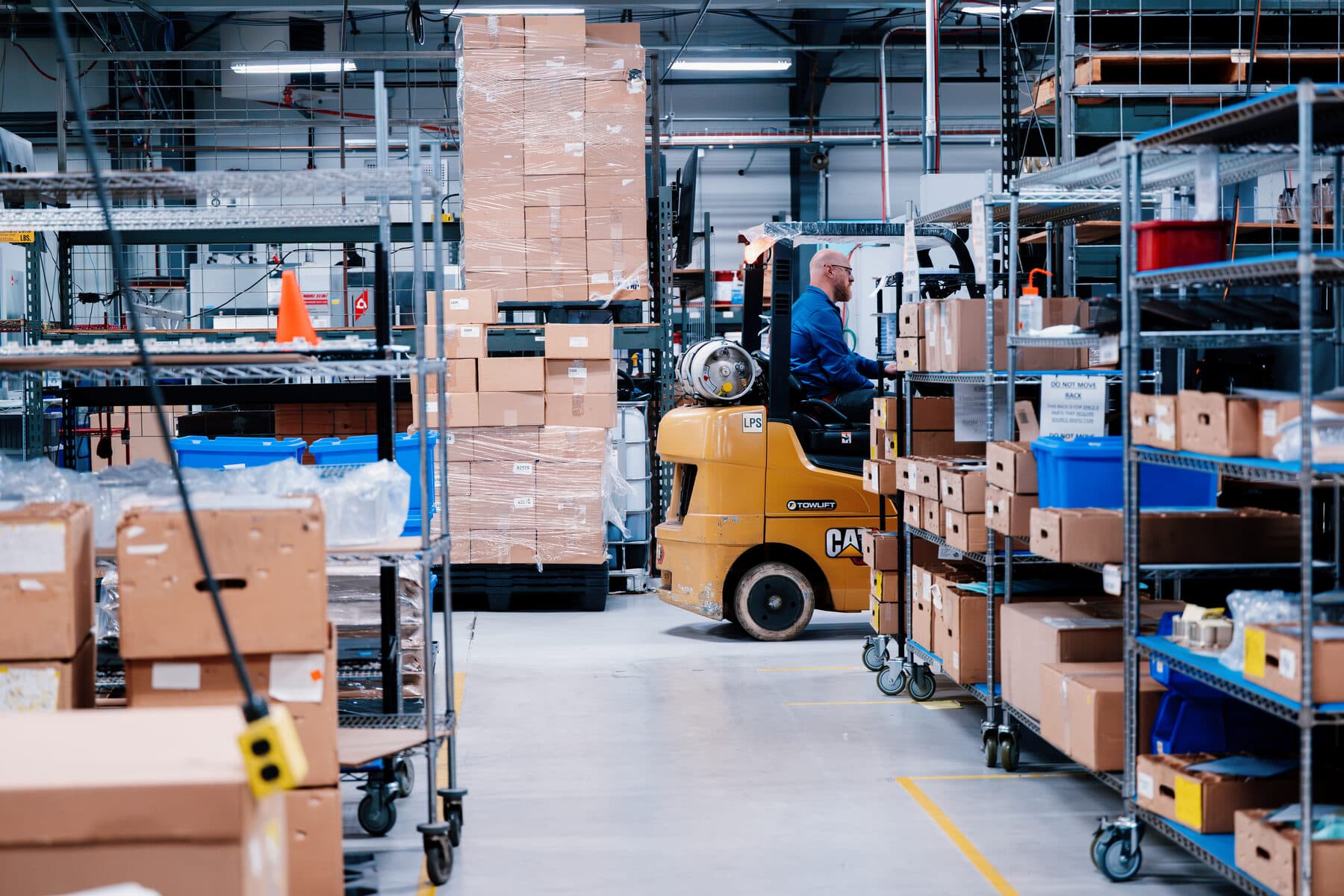 A forklift moving stock between packed shelving in the logistics area