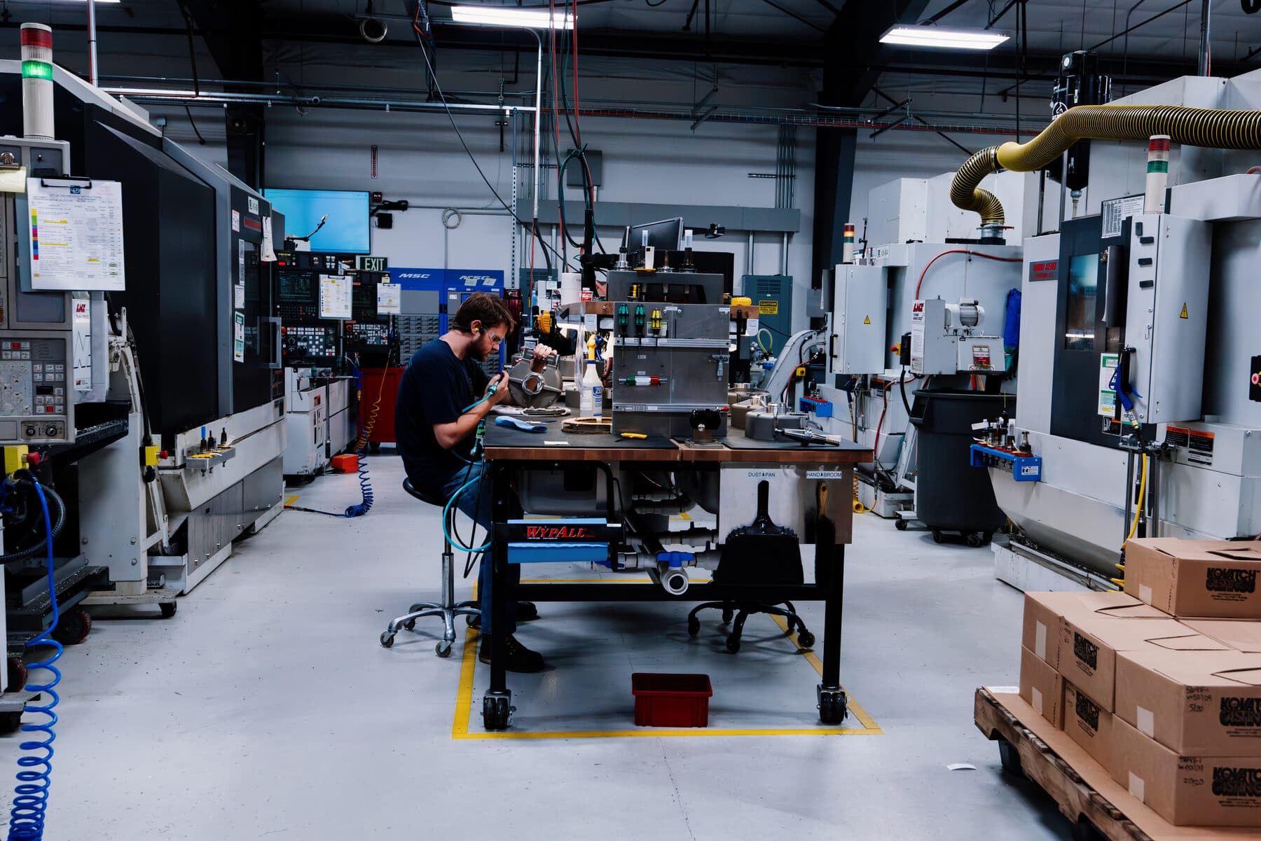 An operator working at a bench between CNC machining centres
