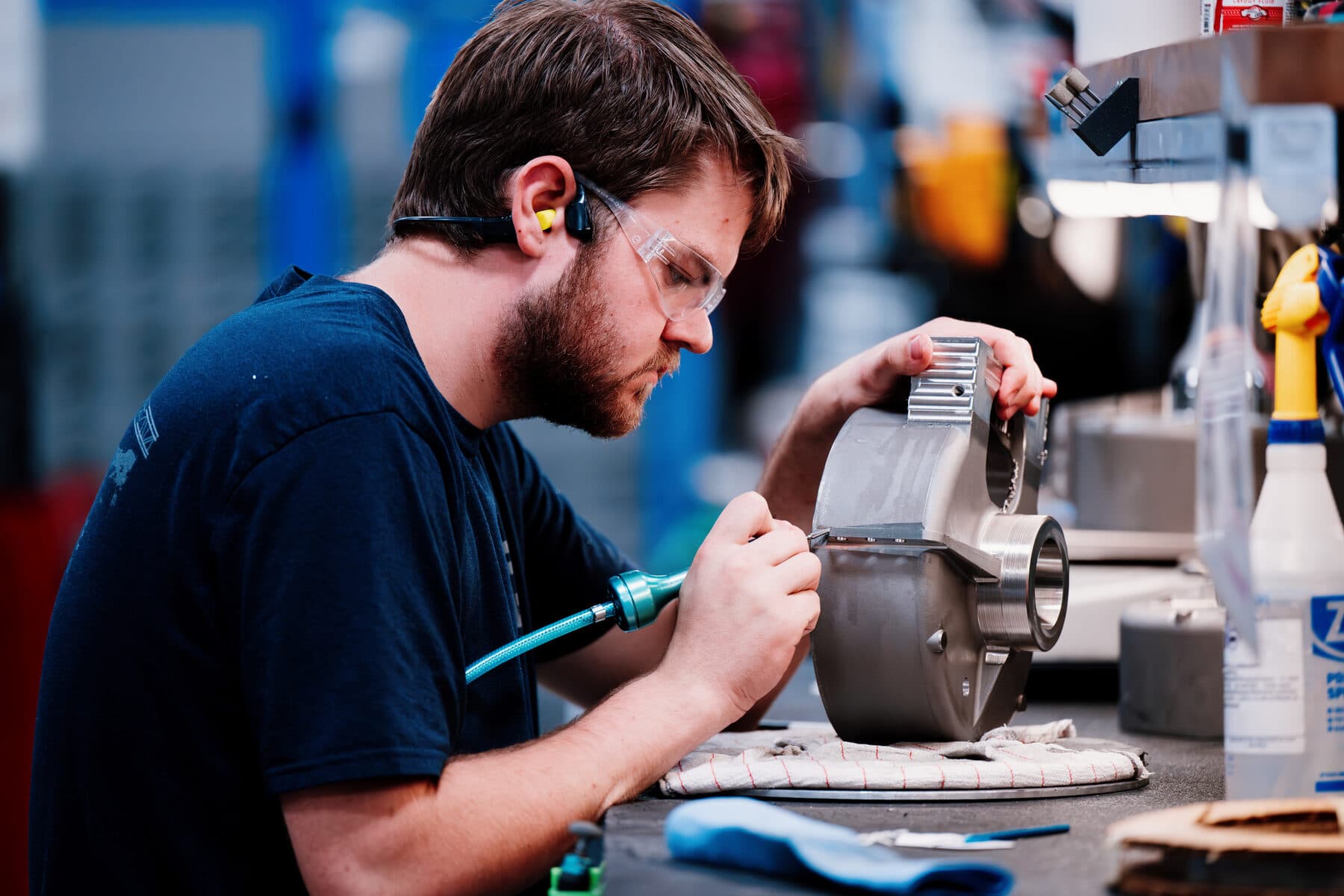 A machinist deburring an aluminium housing at the bench
